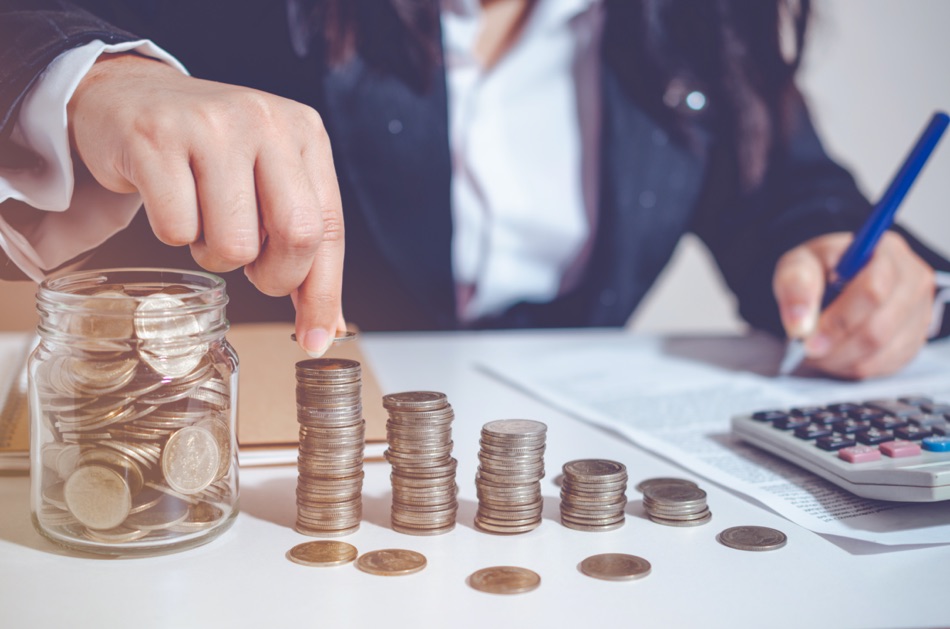 Closeup image businesswoman holding coins putting to stacking coins bank and calculating. concept saving money wealth for finance accounting.