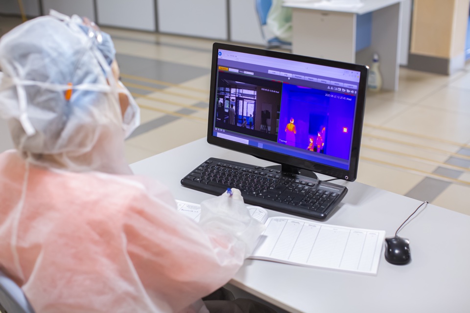 Medical worker monitoring people body temperature via infrared camera detector coronavirus COVID-19 pandemy